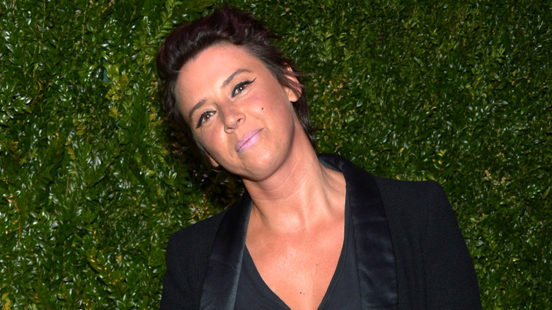 Cat Power smiling in black suit leaves in background