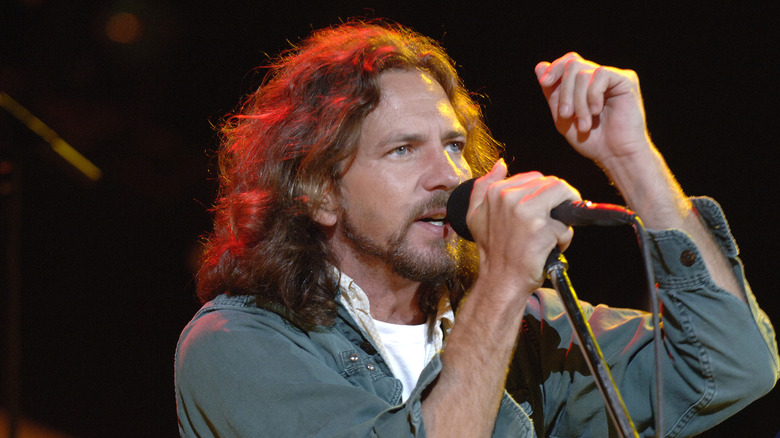 Eddie Vedder holding a microphone close to his face on stage