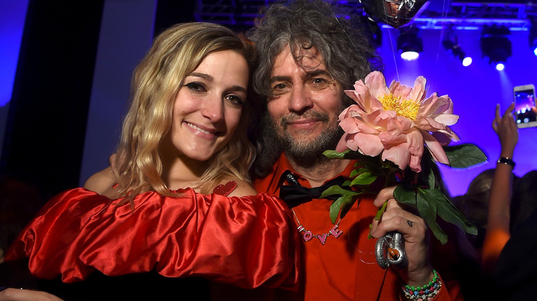 Wayne Coyne holding a large flower posing with Katy Weaver
