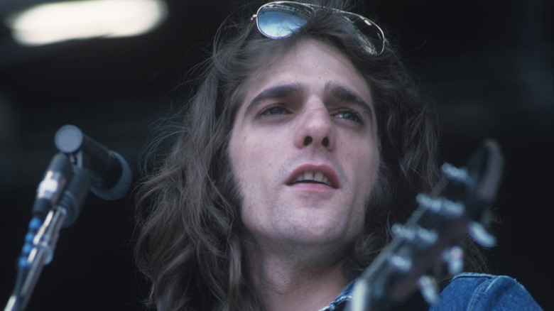 Glenn Frey of the Eagles onstage with guitar looking forward in the 1970s