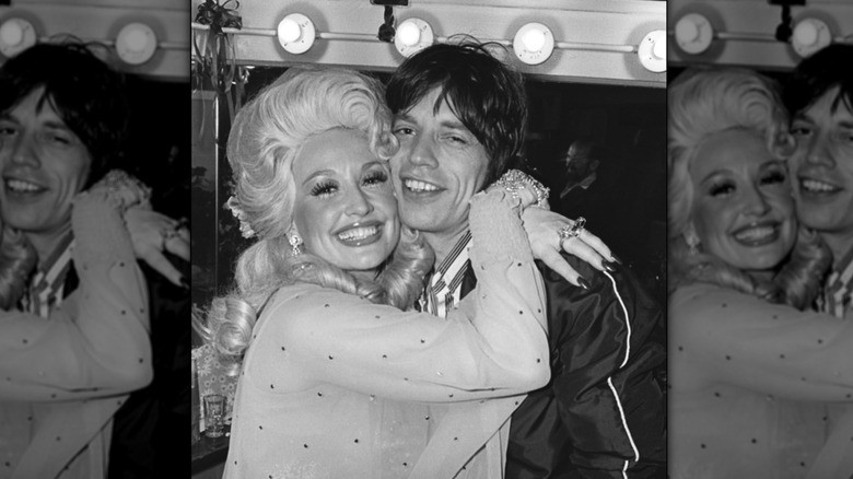 Mick Jagger and Dolly Parton smiling and hugging backstage