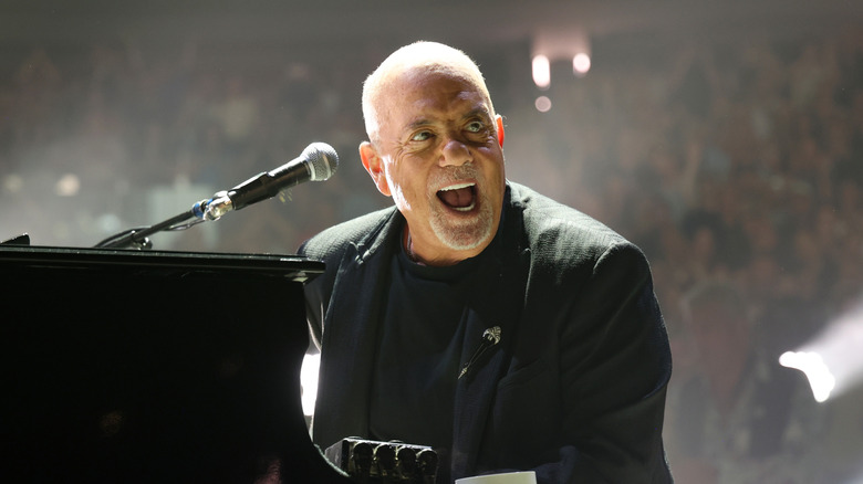 Billy Joel singing at the piano on stage