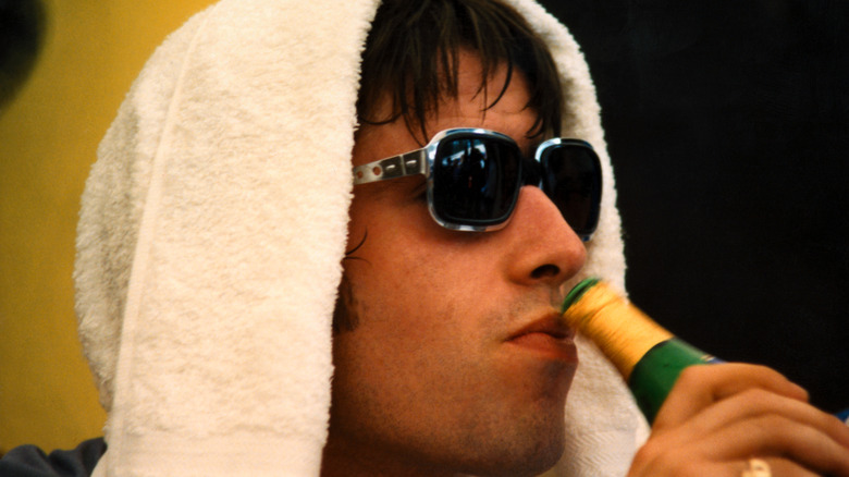 Liam Gallagher drinking a beer with towel on head