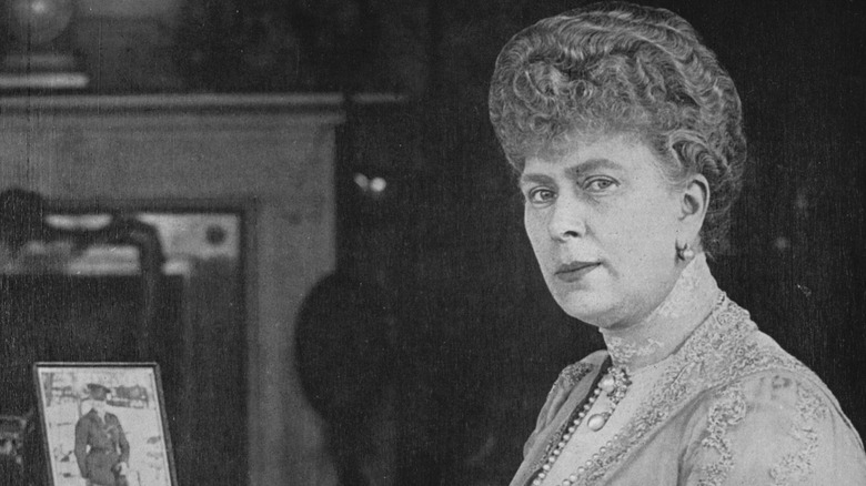 Queen Mary sitting at a desk with framed photos