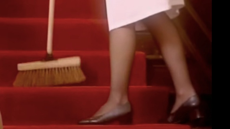Woman sweeping carpet on stairs with brush