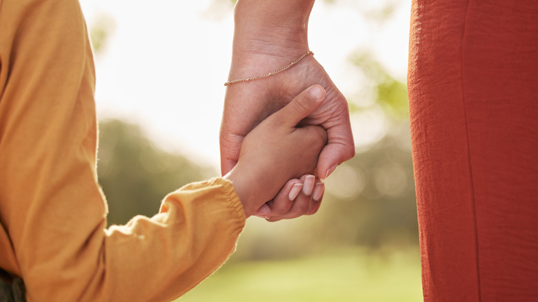 A child holding a parent's hand outdoors