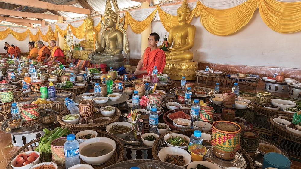 monk behind many trays of food
