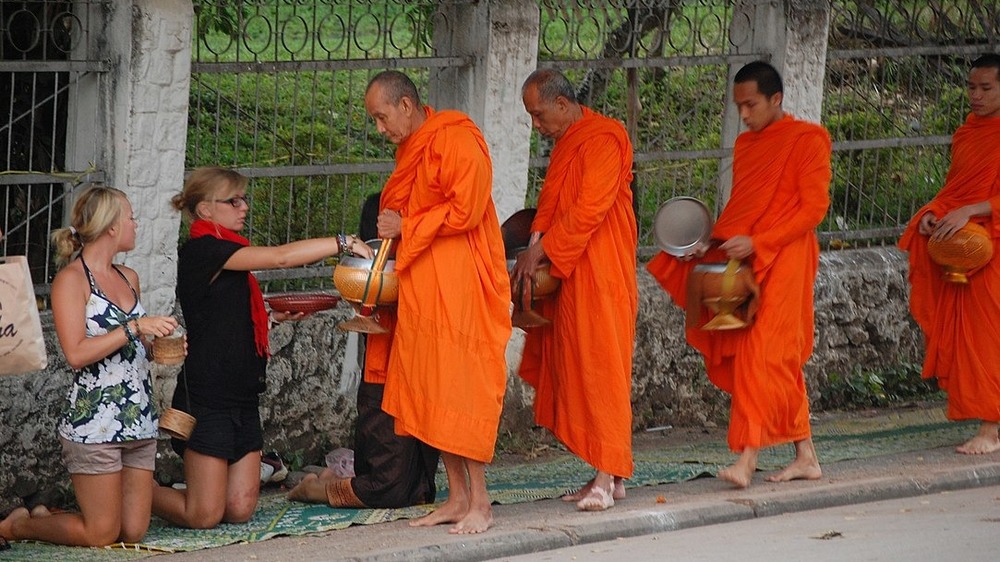 Buddhist monks in orange robes seeking alms