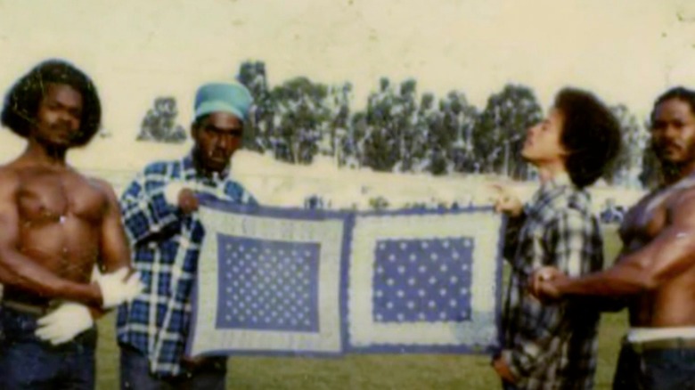 4 men hold up a large blue bandana 
