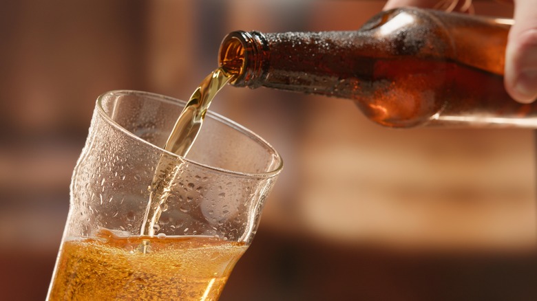 Close up of hand pouring beer from a bottle into a glass