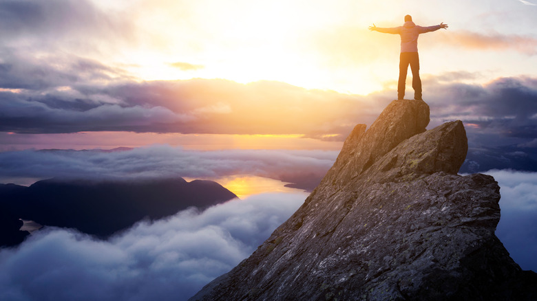 person standing on mountaintop arms spread