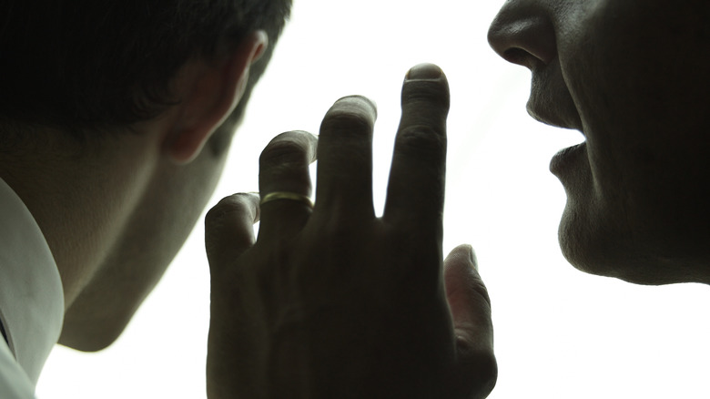 Men whisper together hand white background