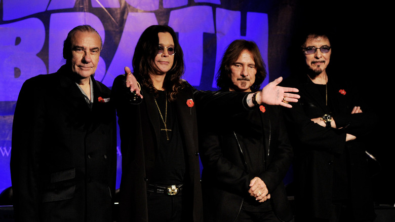 Ozzy Osbourne arms outstretched with the members of Black Sabbath