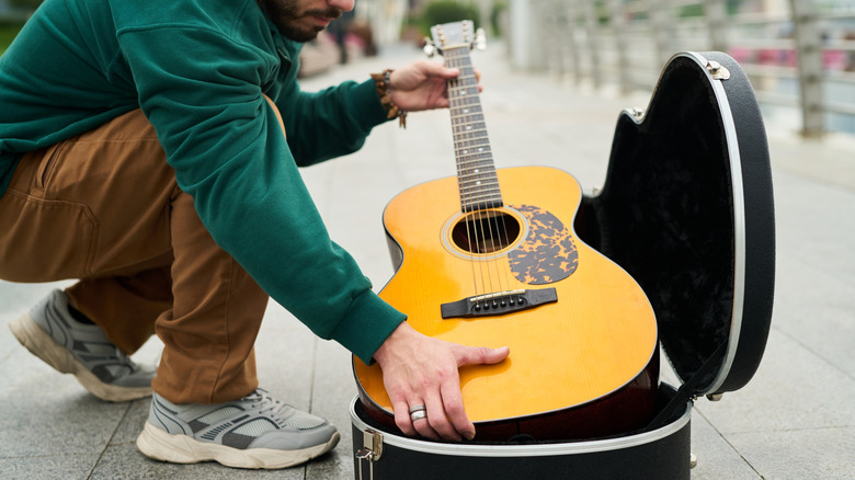 Guy putting guitar in case