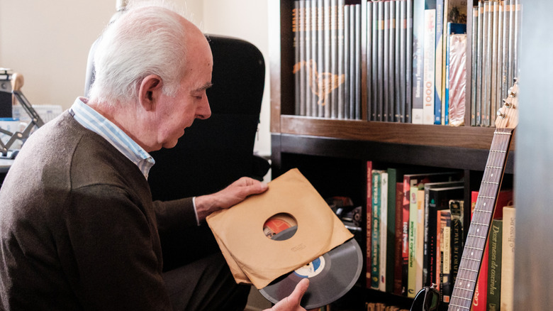 A senior man admiring his vinyl record collection.