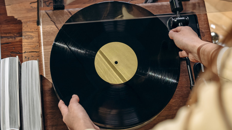 A woman retrieving a vinyl record from a music player.