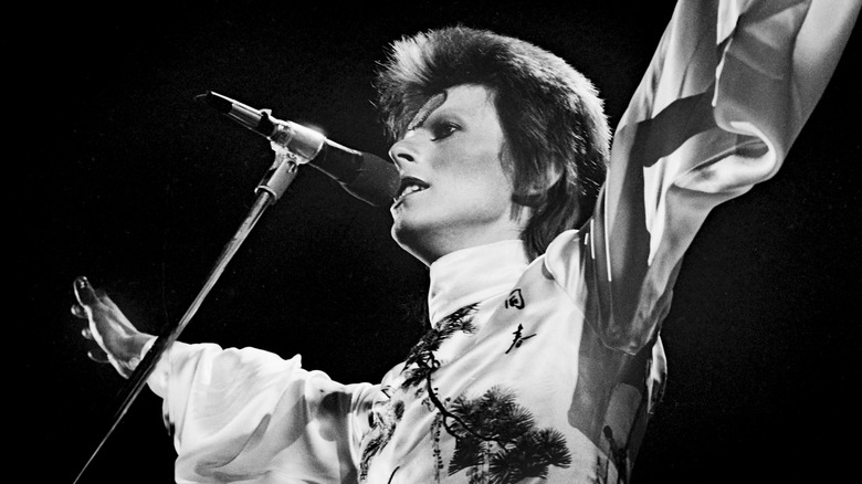 David Bowie performing live with arms stretched out