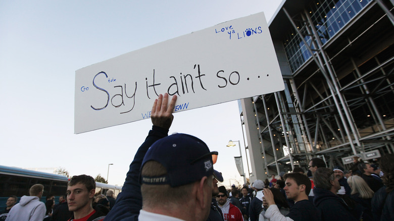 Man holding sign outside Penn State stadium