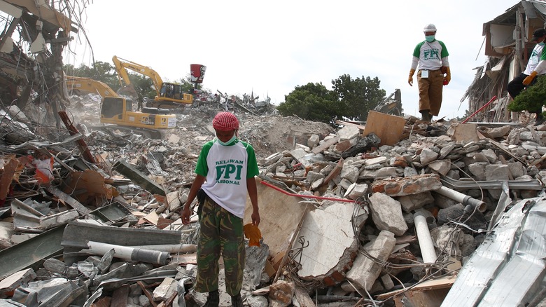 Men standing in earthquake rubble