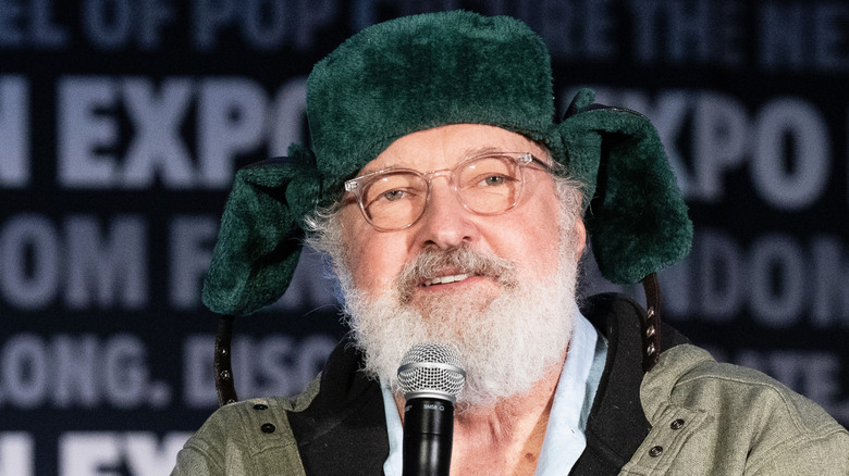 Randy Quaid in furry hat holding microphone