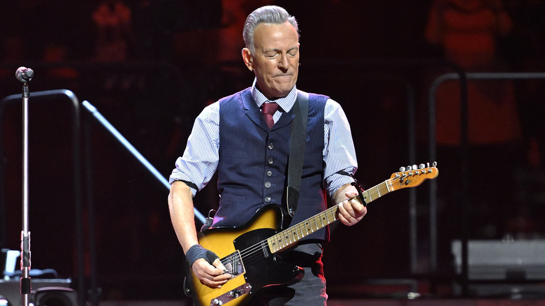 Bruce Springsteen performing on stage with a guitar.