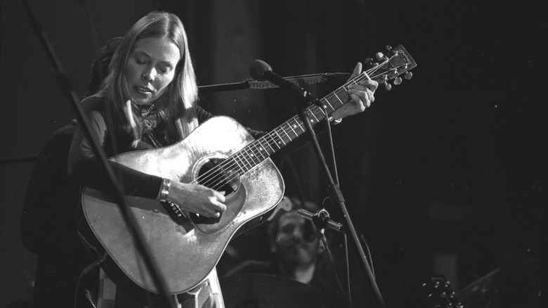 Joni Mitchell playing guitar on stage