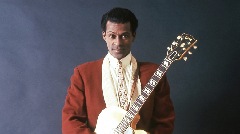 Chuck Berry stood in red suit holding gold guitar