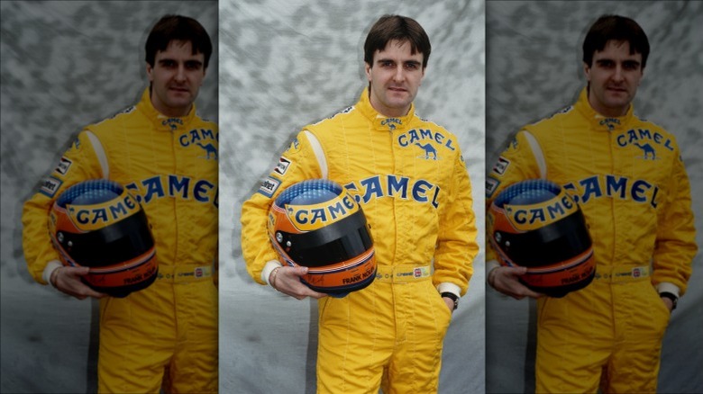 Martin Donnelly posing for a photo in 1990 wearing yellow racing suit holding helmet