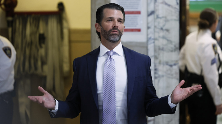 Donald Trump Jr. blue suit beard hands raised