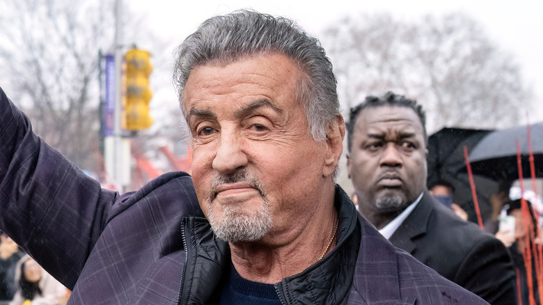 Sylvester Stallone waving in purple jacket