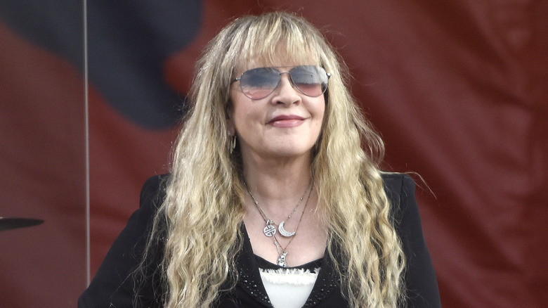 Stevie Nicks smiling in sunglasses onstage outside