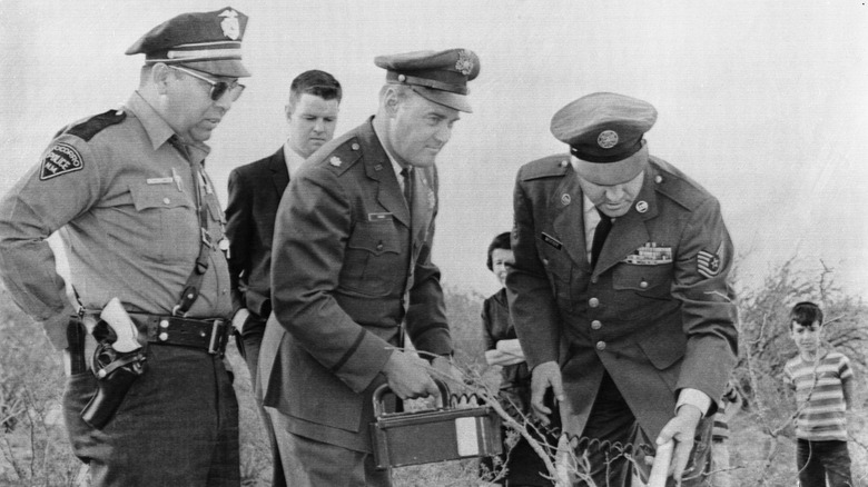 Socorro policeman Lonnie Zamora watches as investigators from Kirtland Air Force Base in Albuquerque use a Geiger counter