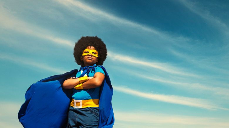 boy wearing a superhero outfit and cape