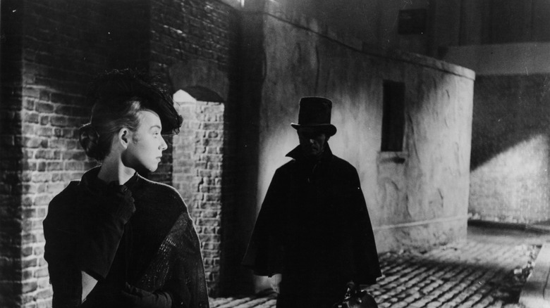 black and white image of a woman in victorian dressed menaced by a pursuing man, film still from jack the ripper, 1959