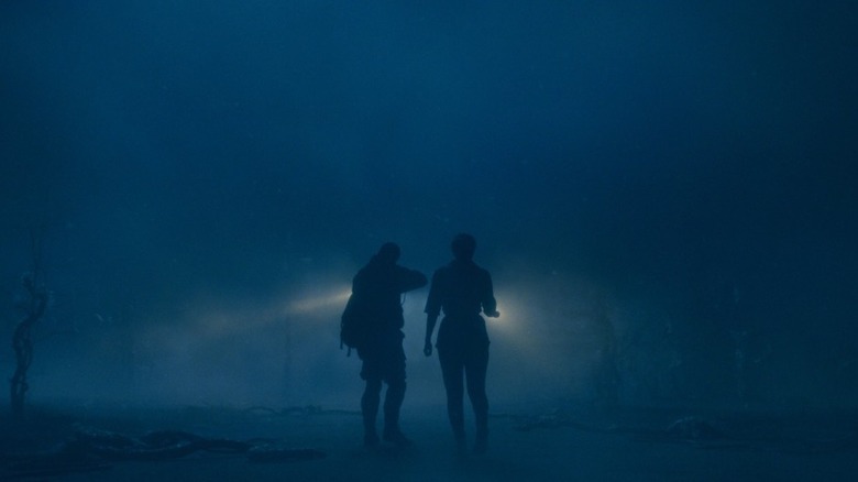 Two silhouettes with shining flashlights ahead in fog and darkness in "Stranger Things" Season 5