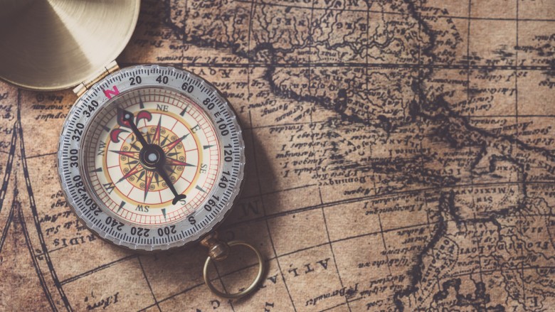 Compass sitting on antique map