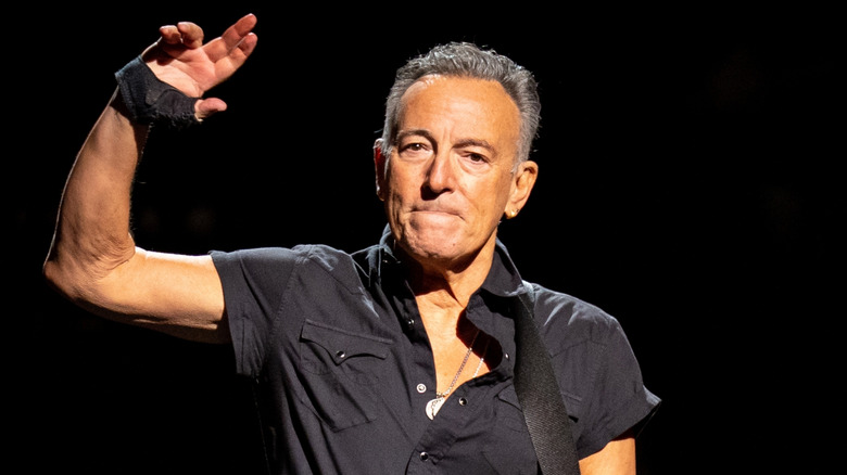 Bruce Springsteen wincing and waving on stage