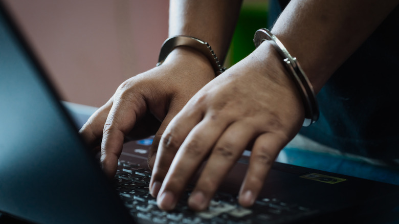 handcuffed person using laptop computer