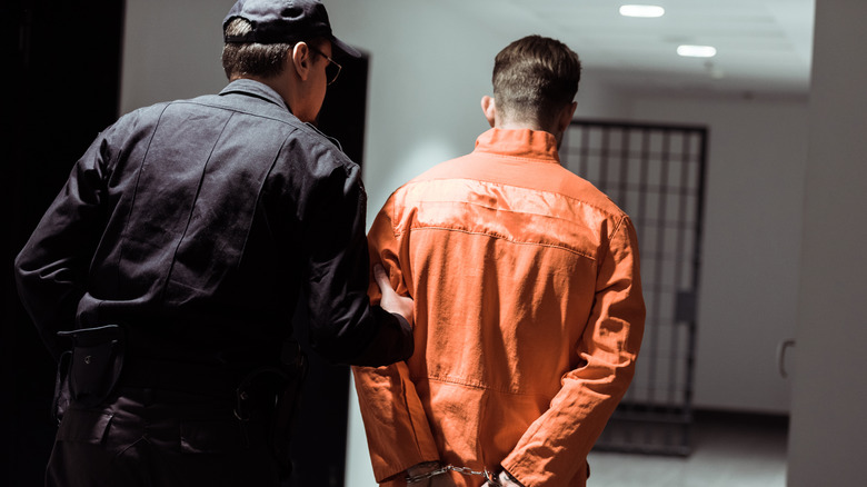 guard moving prisoner down hall