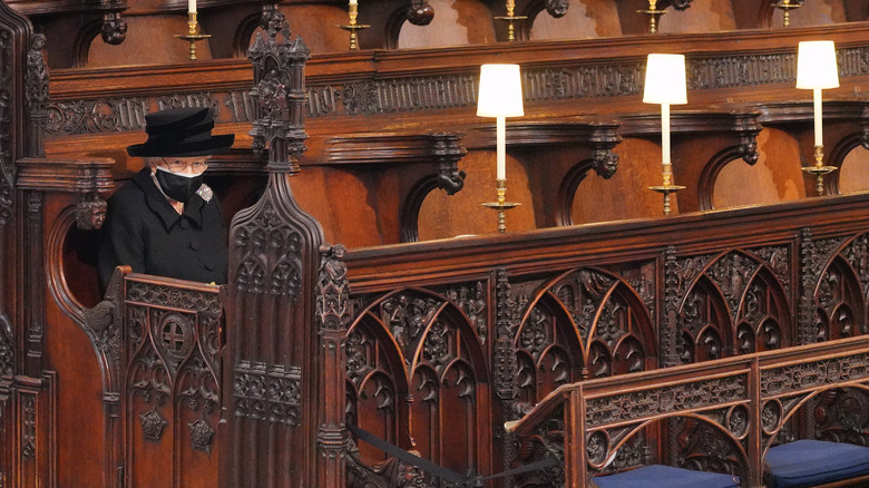 Elizabeth II sits alone in a church pew