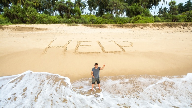 man with "help" written in sand