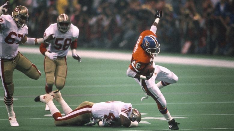 Denver Broncos player stumbling with ball