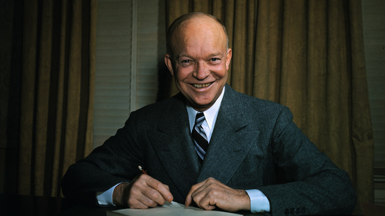eisenhower suit at desk holding pen smiling