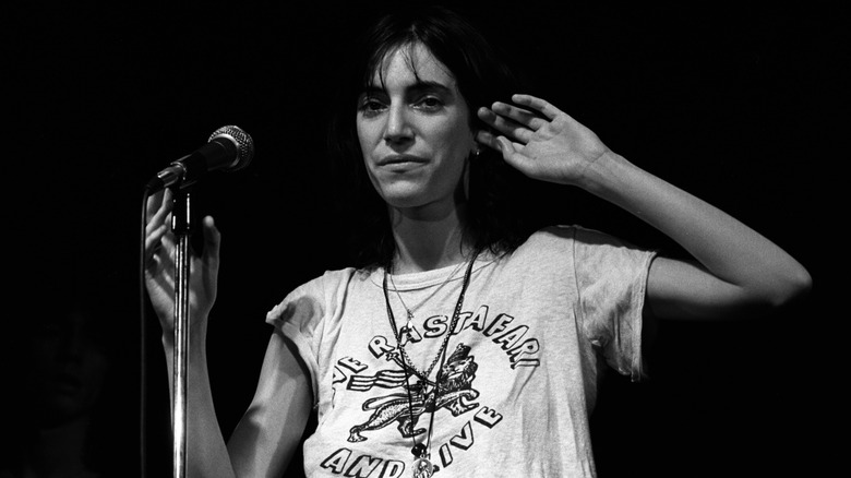 Patti Smith on stage by mic with hand to ear