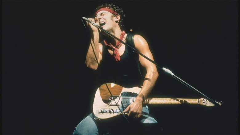 Bruce Springsteen kneeling and singing into microphone