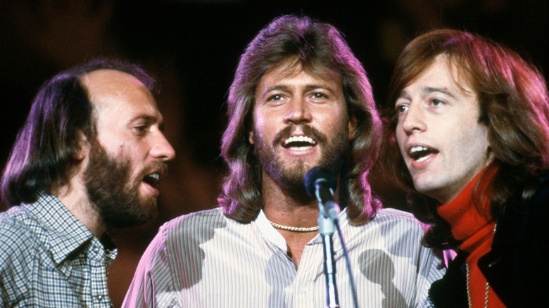 The Bee Gees singing together into shared microphone