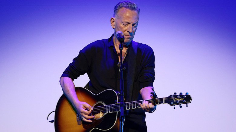 Bruce Springsteen playing acoustic guitar on stage.