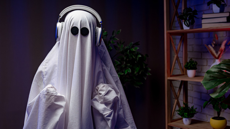 Someone dressed as a ghost wearing headphones
