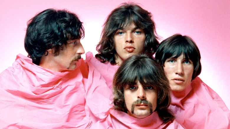 Pink Floyd posing for a portrait in 1968 covered in a pink tarp against a pink background