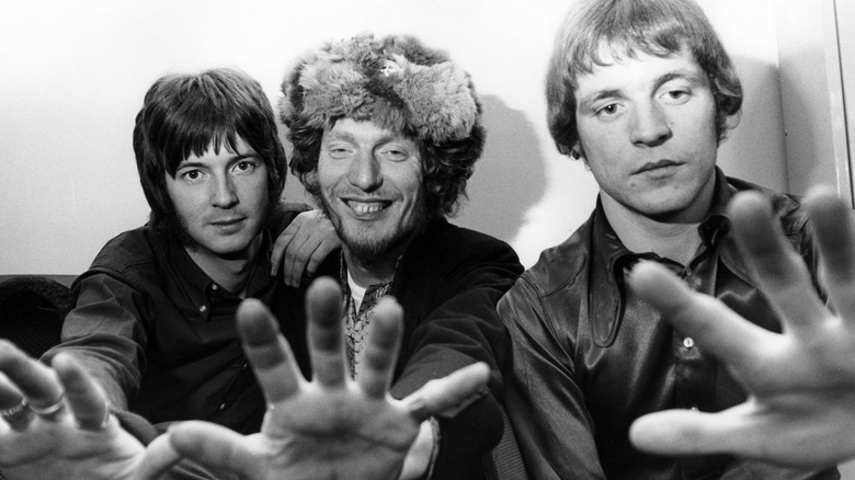 Eric Clapton, Ginger Baker, and Jack Bruce of Cream with hands held toward camera